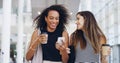 They always have a good time in the office. two young businesswomen chatting and using a smartphone while walking in an Royalty Free Stock Photo