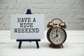 Have a Nice Weekend text and alarm clock on white brick wall and wooden background Royalty Free Stock Photo