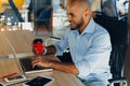 Have a nice working day. Confident young african american businessman working on laptop and talking on cell phone while sitting at Royalty Free Stock Photo