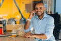 Have a nice working day. Confident young african american businessman working on laptop and talking on cell phone while sitting at Royalty Free Stock Photo