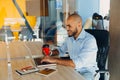 Have a nice working day. Confident young african american businessman working on laptop and talking on cell phone while sitting at Royalty Free Stock Photo