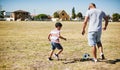 We have a soccer player in the making here. a cheerful little boy and his father playing soccer together outside on a Royalty Free Stock Photo