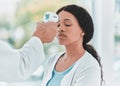 Have you been feeling warm lately. a doctor scanning a patients temperature using a thermometer.