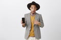 Have you checked new smartphone in shops. Thrilled amazed dark-skinned male model in stylish hat and jacket, showing Royalty Free Stock Photo