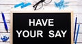 HAVE YOUR SAY written on a black note-board next to blue paper clips, pencils and a pen Royalty Free Stock Photo