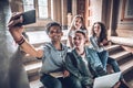 Having the best time with friends. Group of students studying while sitting on stairs in university and making selfie on smart