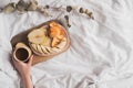 Having a breakfast in bed from a tray with fruits and tea in white clean bed. Mindful and quiet living, slow life, simple Royalty Free Stock Photo