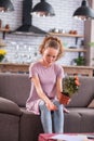 Miserable ginger young lady sitting on grey couch with pot