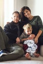 Having a chilled out day at home. Portrait of a cheerful young family seated on a sofa together at home during the day.