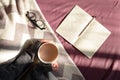 Having coffee and reading in bed on lazy sunny morning. Top ciew of female hands holding steaming cup of hot cocoa reading in bed