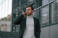 Having conversation by phone. Handsome man in formal clothes is outdoor near the business building Royalty Free Stock Photo