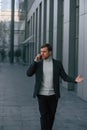 Having conversation by phone. Handsome man in formal clothes is outdoor near the business building Royalty Free Stock Photo