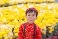 Having fun asian kid at marigold garden. Portrait of funny kid wearing Vietnamese traditional dress Ao Dai at Tet holiday