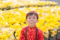 Having fun asian kid at marigold garden. Portrait of funny kid wearing Vietnamese traditional dress Ao Dai at Tet holiday