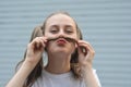 Having fun teen age girl - smiling and making mustache with strand of hair. Outdoor close up portrait Royalty Free Stock Photo