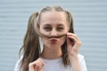 Having fun teen age girl - smiling and making mustache with strand of hair. Outdoor close up portrait Royalty Free Stock Photo