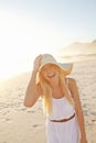 Having a fun time at the beach. Portrait of a gorgeous young woman wearing a white dress and sunhat on the beach. Royalty Free Stock Photo