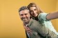 Having fun together. Happy middle aged spouses taking selfie, woman piggyback riding on her husband& x27;s back Royalty Free Stock Photo
