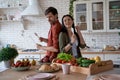 Having fun. Young playful family couple dancing and singing while preparing healthy breakfast in the modern kitchen at Royalty Free Stock Photo