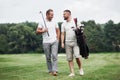 Having good time. Two friends walking through the lawn with golf equipment and talking Royalty Free Stock Photo