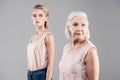 Old grey-haired woman taking look behind while her daughter