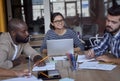 Having a meeting. Three young multicultural business people working together in the modern office, discussing project or Royalty Free Stock Photo