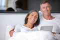 Having a relaxed weekend together. Portrait of a happy mature couple sitting in bed with a digital tablet. Royalty Free Stock Photo