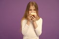 Having snacks. Child eat donut on violet background. Little girl with glazed ring doughnut on purple background. Kid Royalty Free Stock Photo