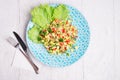 Hawaii style vegetarian raw eating salad/ served in beauiful blue plate on white table. flat lay