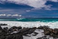 Hawaiian beach; volcanic rocks and form on shoreline; wave breaking offshore. Pacific, blue sky and clouds in distance. Royalty Free Stock Photo