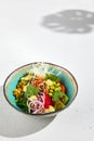 Hawaiian cuisine - Poke bowl with salmon, avocado, edamame and vegetables. Pokebowl in ceramic dish on white background with Royalty Free Stock Photo