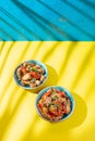 Hawaiian pinapple chicken in blue bowls on yellow blue background. Trendy sunlight effect