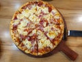 Hawaiian pizza divided into eight slices on wooden tray.