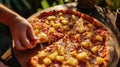 A Hawaiian pizza featuring pineapple and ham with hands reaching for a slice Royalty Free Stock Photo