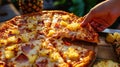 A Hawaiian pizza featuring pineapple and ham with hands reaching for a slice Royalty Free Stock Photo