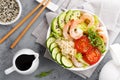 Hawaiian poke bowl with shrimps, rice and vegetables, healthy Buddha bowl with prawns, rice, avocado, cucumber, tomato and lettuce