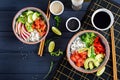Hawaiian salmon fish poke bowl with rice, avocado, paprika, cucumber, radish, sesame seeds and lime. Buddha bowl. Diet food. Top