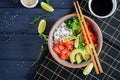 Hawaiian salmon fish poke bowl with rice, cucumber, radish, sesame seeds and lime. Royalty Free Stock Photo