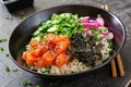 Hawaiian salmon fish poke bowl with rice, radish,cucumber, tomato, sesame seeds and seaweeds. Royalty Free Stock Photo