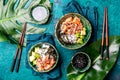 Hawaiian salmon poce with avocado, rice and sesamo served in bowls on tropical leaves. Turquoise slate background. Top Royalty Free Stock Photo