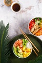 Hawaiian trendy poke bowls with salmon, heura soy protein or vegan chicken, variety vegetables, mango served in bowl on tropical