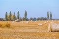 Hay bail harvesting in wonderful autumn farmers field landscape with hay stacks Royalty Free Stock Photo