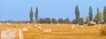 Hay bail harvesting in wonderful autumn farmers field landscape with hay stacks Royalty Free Stock Photo