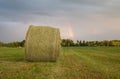 Hay bale on agricultural field after rain, rainbow in the background