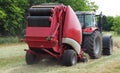 Hay baler machine pulled by a red tractor on a freshly cut field Royalty Free Stock Photo