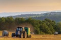 A hay baler at work in an Umbrian field as the sun sets. Royalty Free Stock Photo