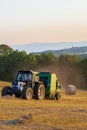 A hay baler at work in an Umbrian field as the sun sets Royalty Free Stock Photo