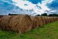 Hay bales on the field after harvest .Yellow golden bales of wheat hay straw in stubble field with expressive cloudy blue sky in Royalty Free Stock Photo