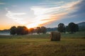 Hay bales rolled on field at sunrise with fog creates amazing sky in early summer Royalty Free Stock Photo