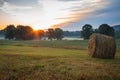 Hay bales rolled on field at sunrise with fog creates amazing sky in early summer Royalty Free Stock Photo